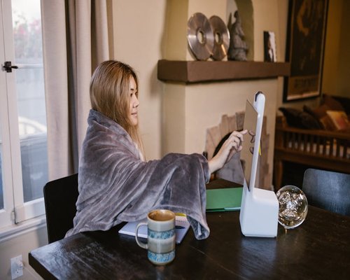 Person adjusting monitor distance in a cozy home office
